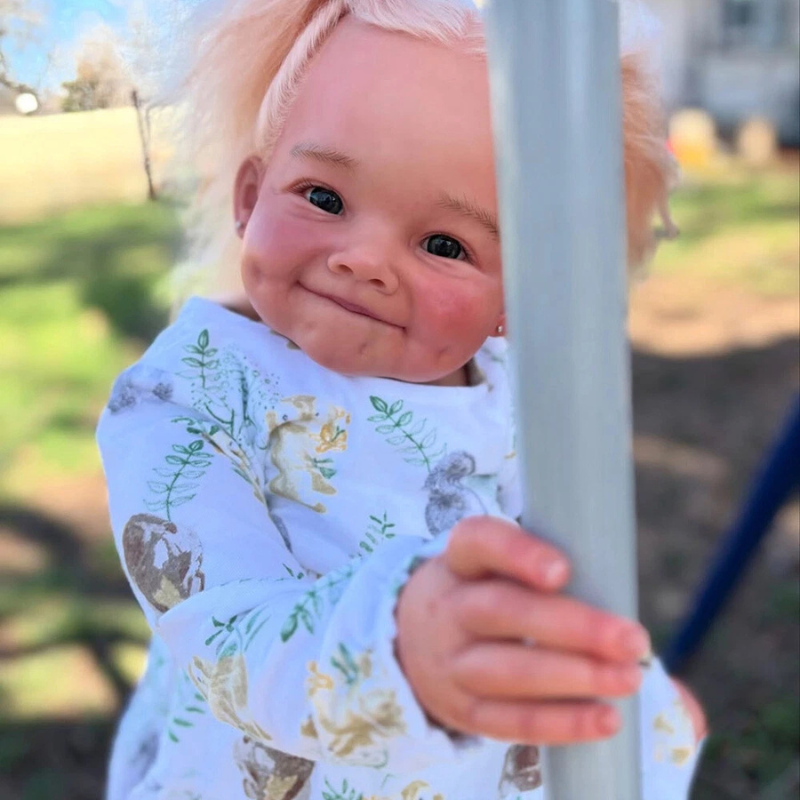 Stella Reborn Girl doll, 28 inches tall, sitting on a swing, holding the side with her hand to keep balance, wearing a cute outfit, in a playground setting.
