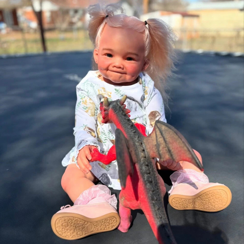 Stella Reborn Girl doll, 28 inches tall, handmade with love and tender realism, sitting on the ground playing with her dragon toy, wearing a cute outfit.